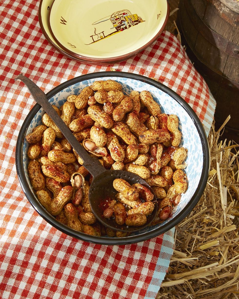 spiced roasted peanuts in a bowl with a spoon for serving on a red gingham tablecloth